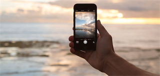 Person tar bilde av solnedgangen med mobilen