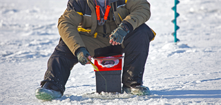 Sitter og fisker på isen